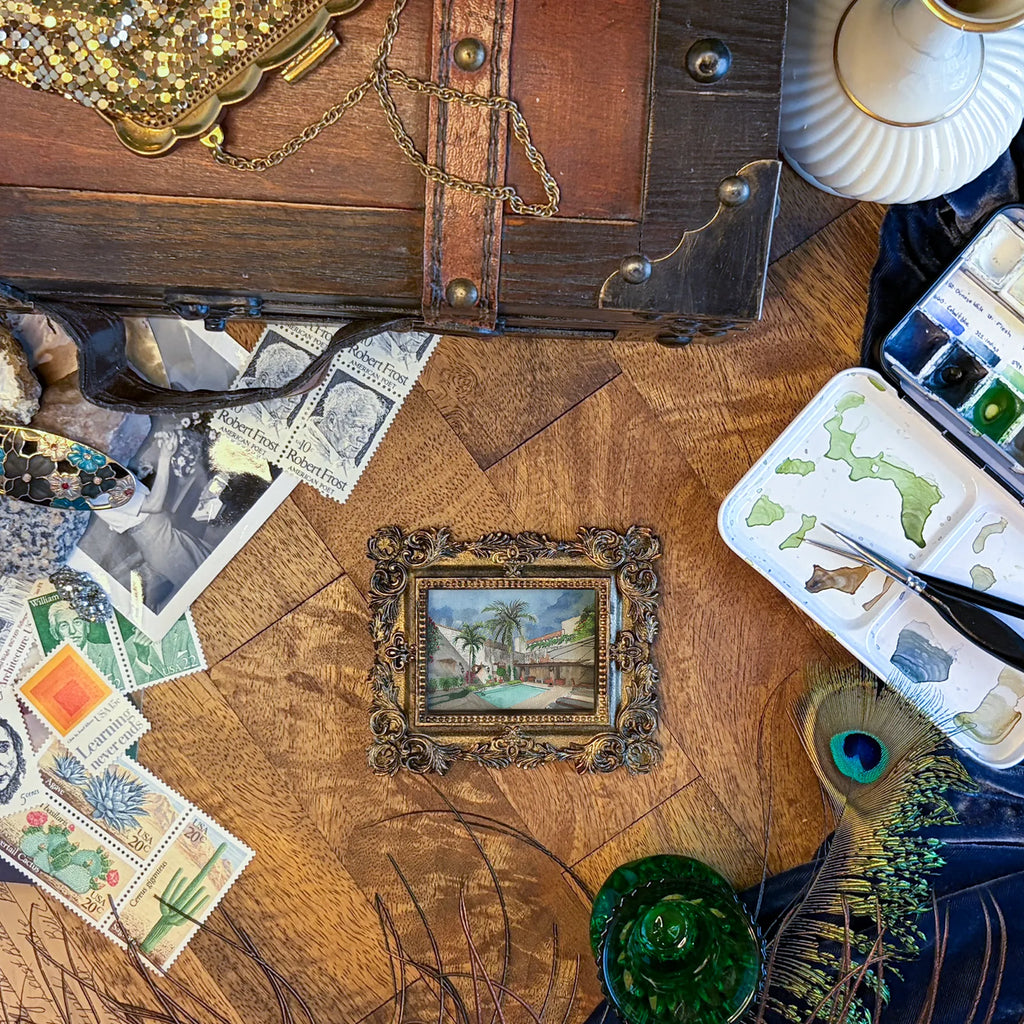Art fairy magic themed craft items on a wooden table, including a small framed picture and jewelry