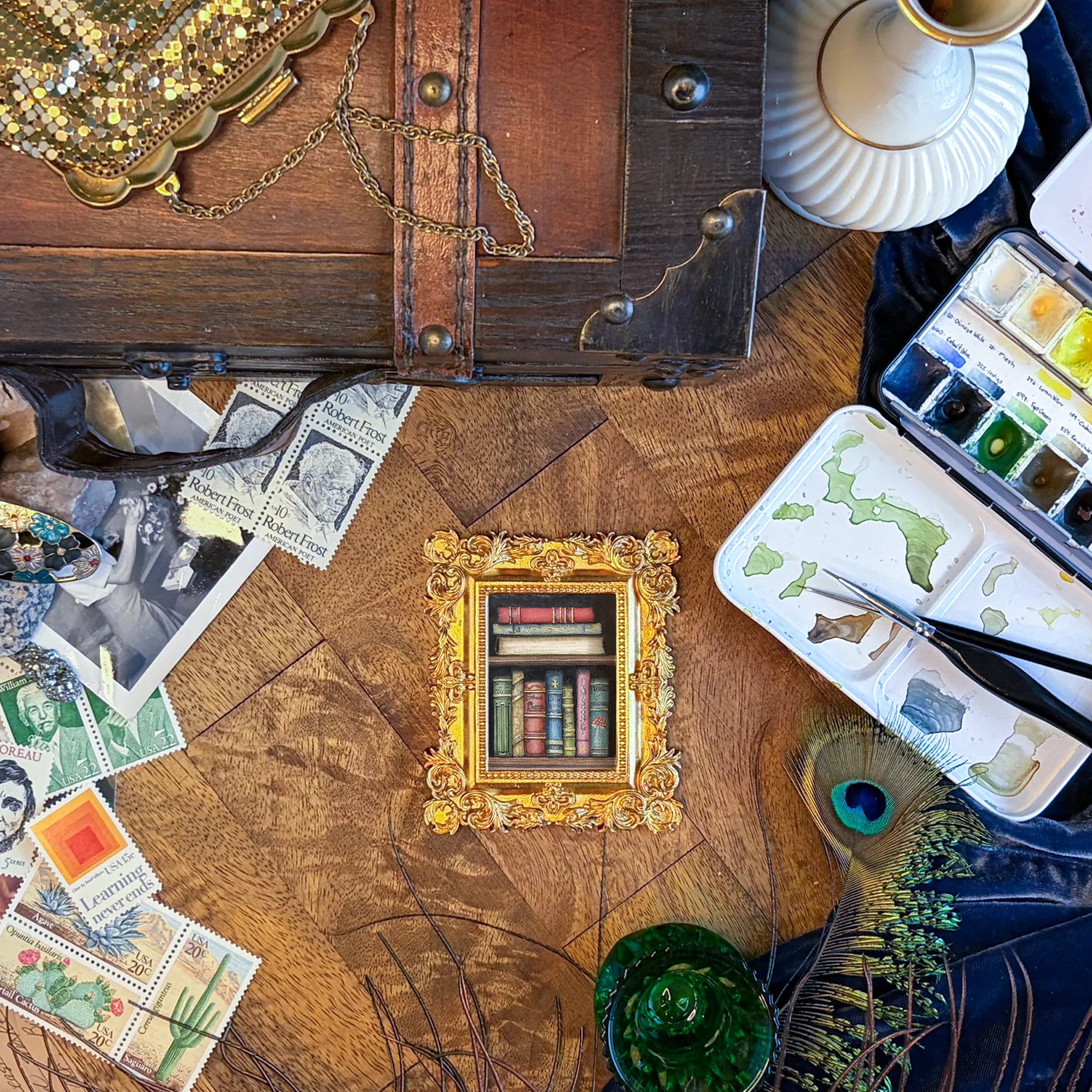 Art supplies on a wooden table, including a fairy magic themed frame, stamps, and paint tubes.