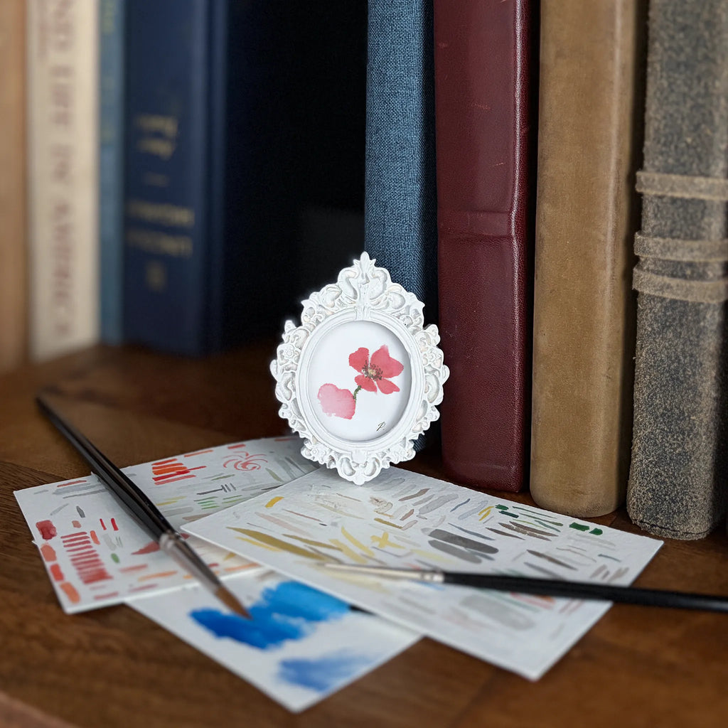 Art and Magic themed fairy books with a framed flower photo resting on a table