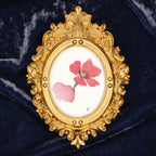 Art fairy magic in a gilded oval frame with pink flower paint on a dark blue fabric background