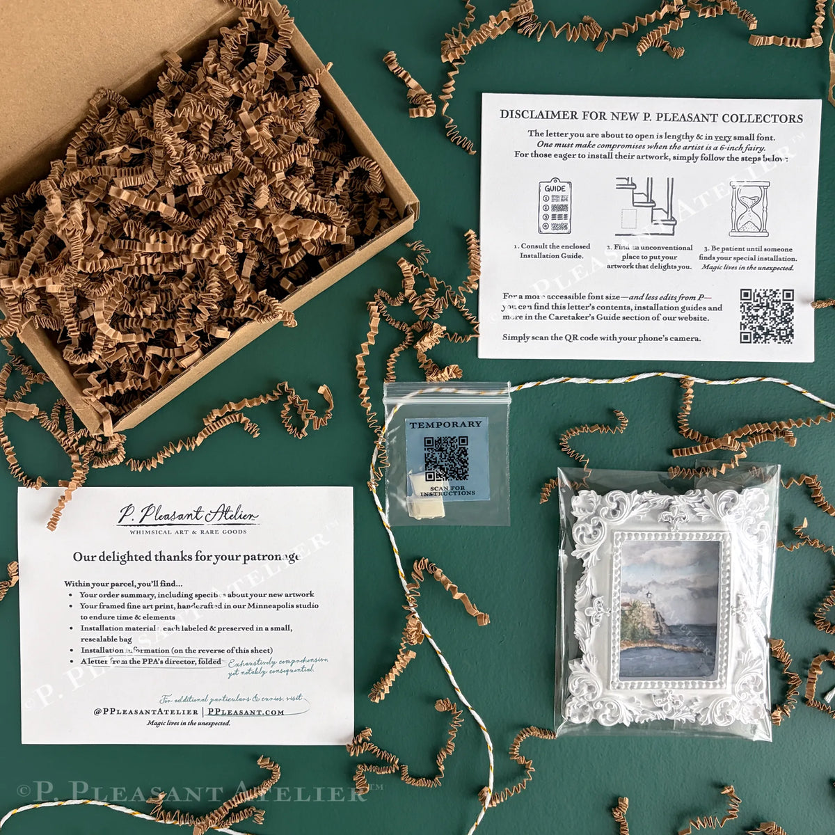 A curated gift set flat lay on a dark green background, featuring a cardboard box filled with brown paper shred, a framed art print with a white scalloped border, installation putty with a QR code for installation instructions, a letter from the P. Pleasant Director, Bleeker Garfield, and a thank you card from P. Pleasant Atelier.