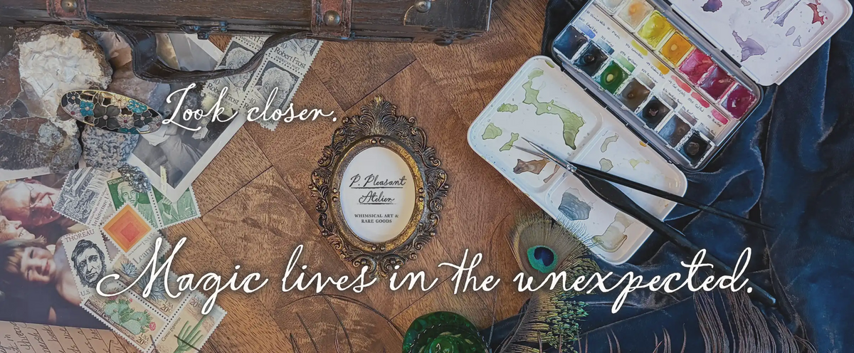 A styled flat-lay scene with a vintage watercolor paint palette, paintbrush, scattered postcards, a small framed print, and decorative objects on a wooden surface. Large white script text overlays read 'Look closer. Magic lives in the unexpected.'