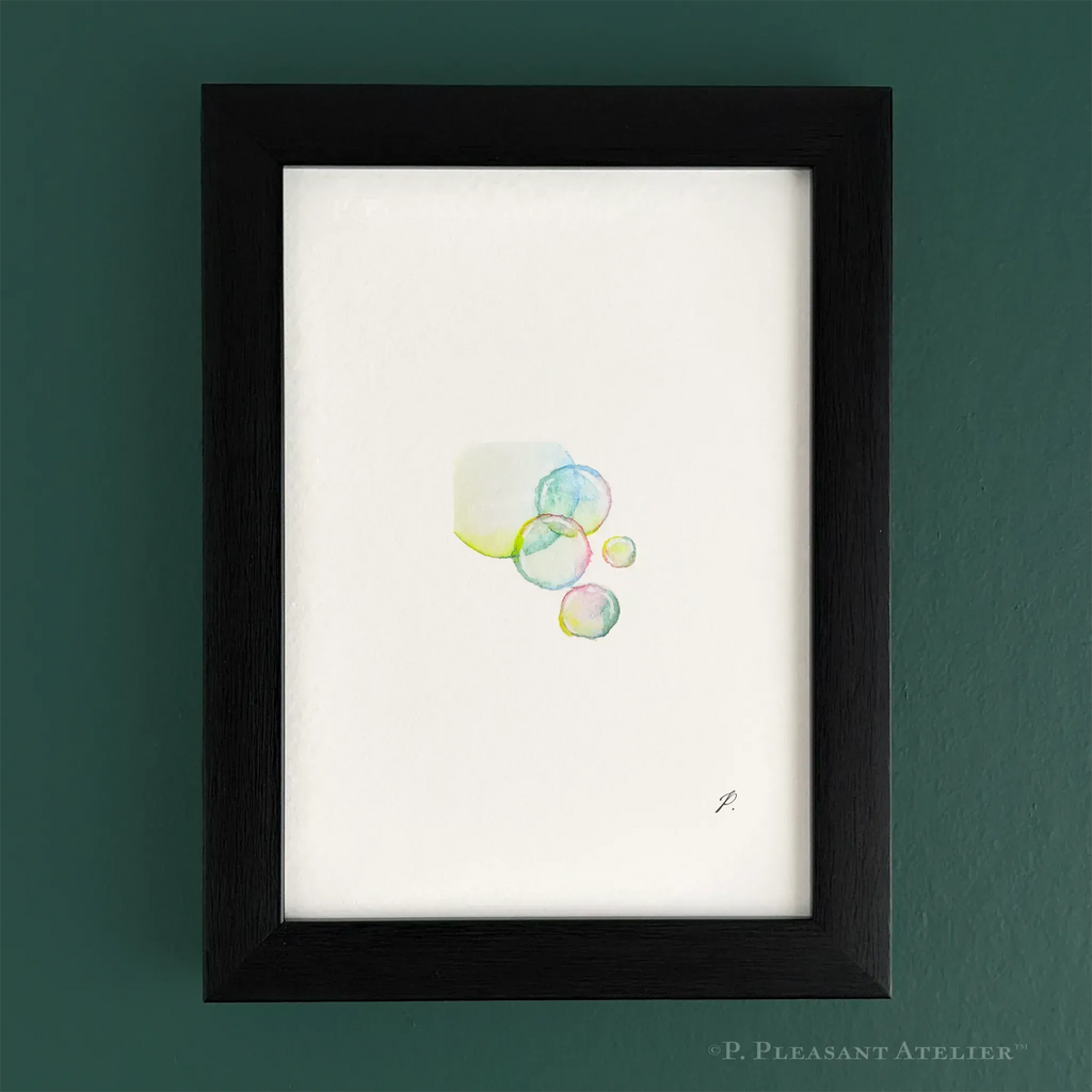 Framed minimalist art print featuring a cluster of translucent watercolor bubbles on a white background, housed in a black wood frame and mounted on a dark green wall. Signed by the artist with "P."
.