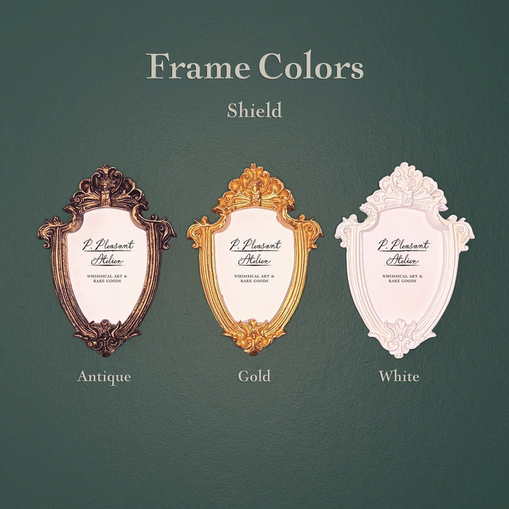 Three decorative shield-shaped picture frames shown on a dark green background with the text 'Frame Colors Shield' and labels 'Antique', 'Gold', and 'White'.