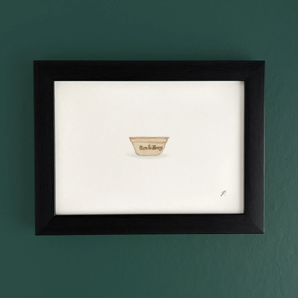 Art print in a dark wooden frame on a teal wall, with a small cup shaped emblem near the bottom