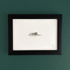Art fairy magic illustration in a black frame on a teal wall, showing a small mouse near paper