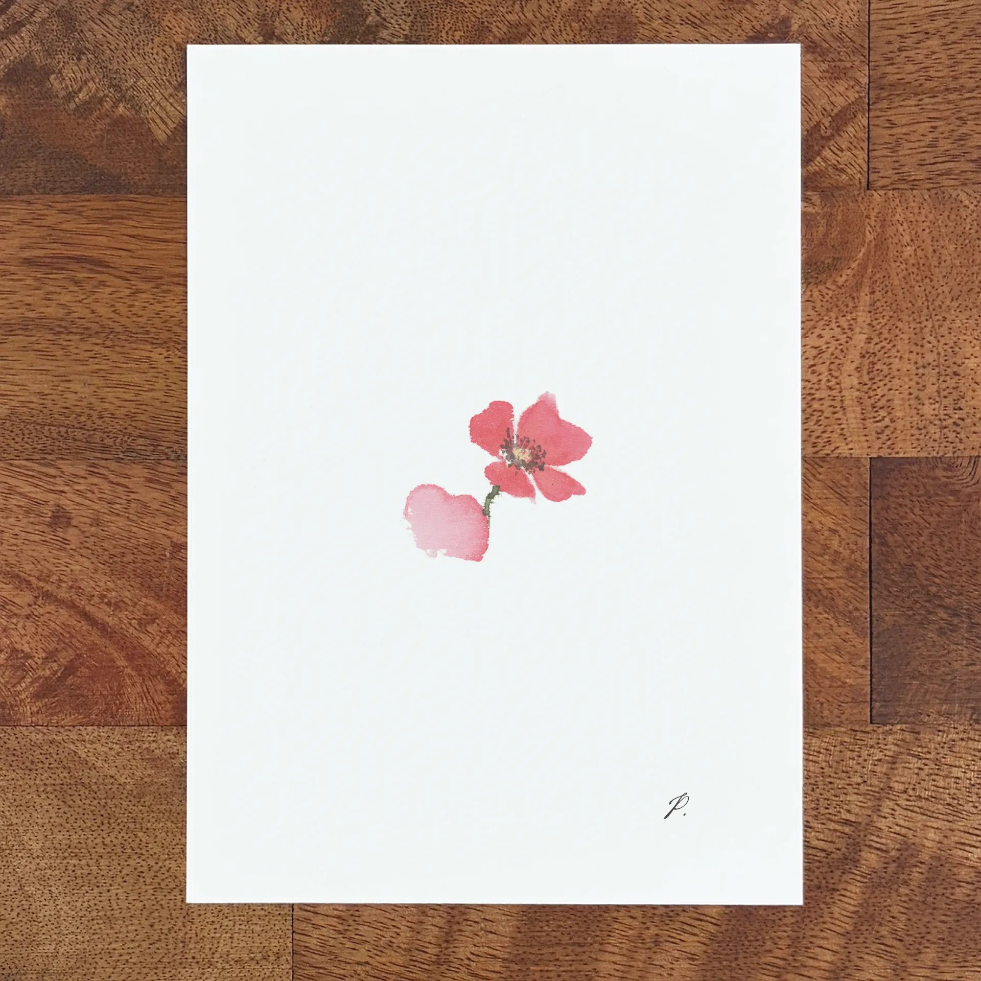 Art on white paper shows a small pink fairy flower with a dark stem on a wooden table