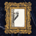 An ornate gold baroque-style picture frame containing a black and white sketch of a woodpecker on a tree trunk, set against a dark navy blue velvet fabric background.
